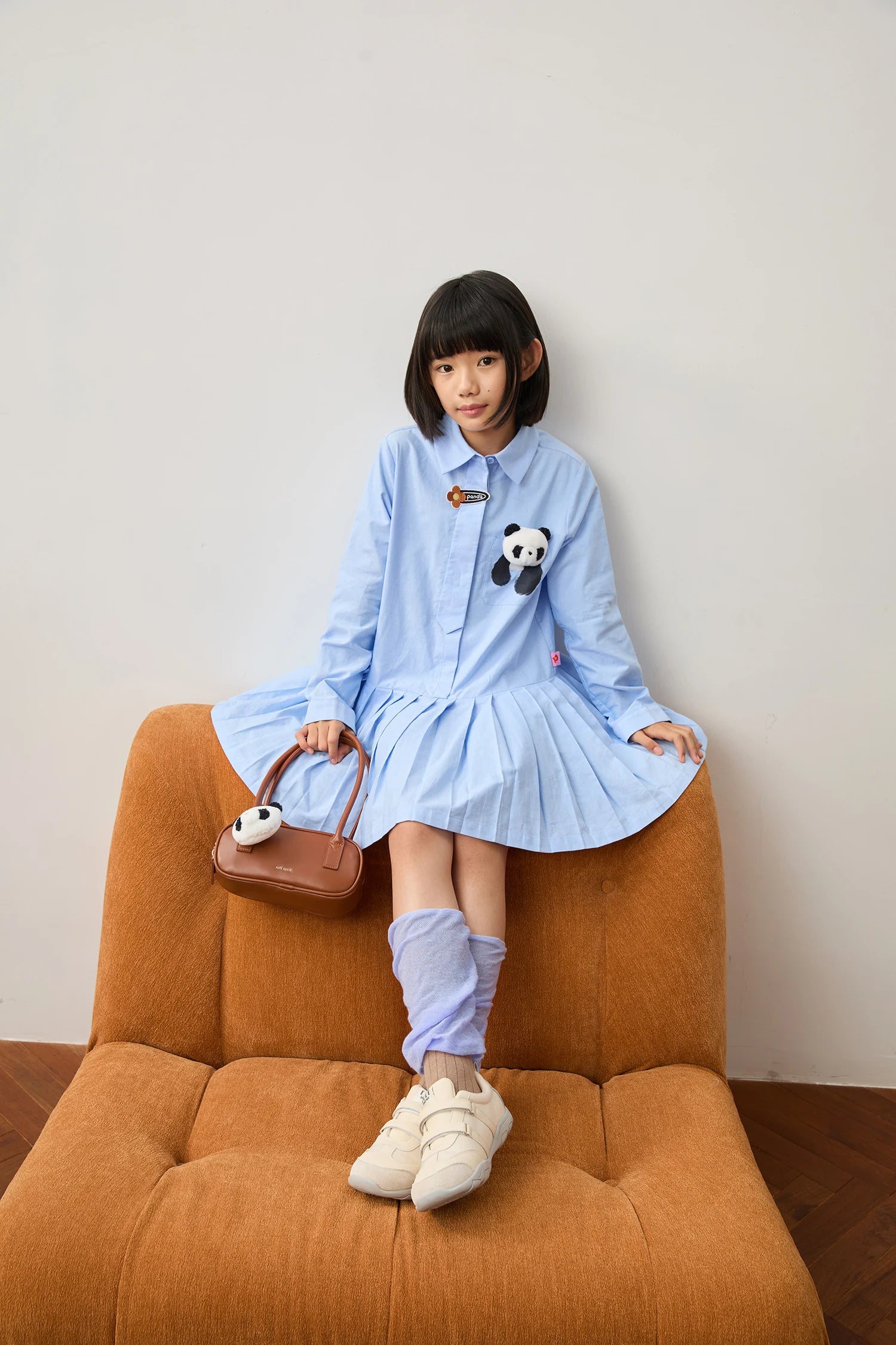Blue panda pleated shirt dress with blue colour-block socks; seated styled look