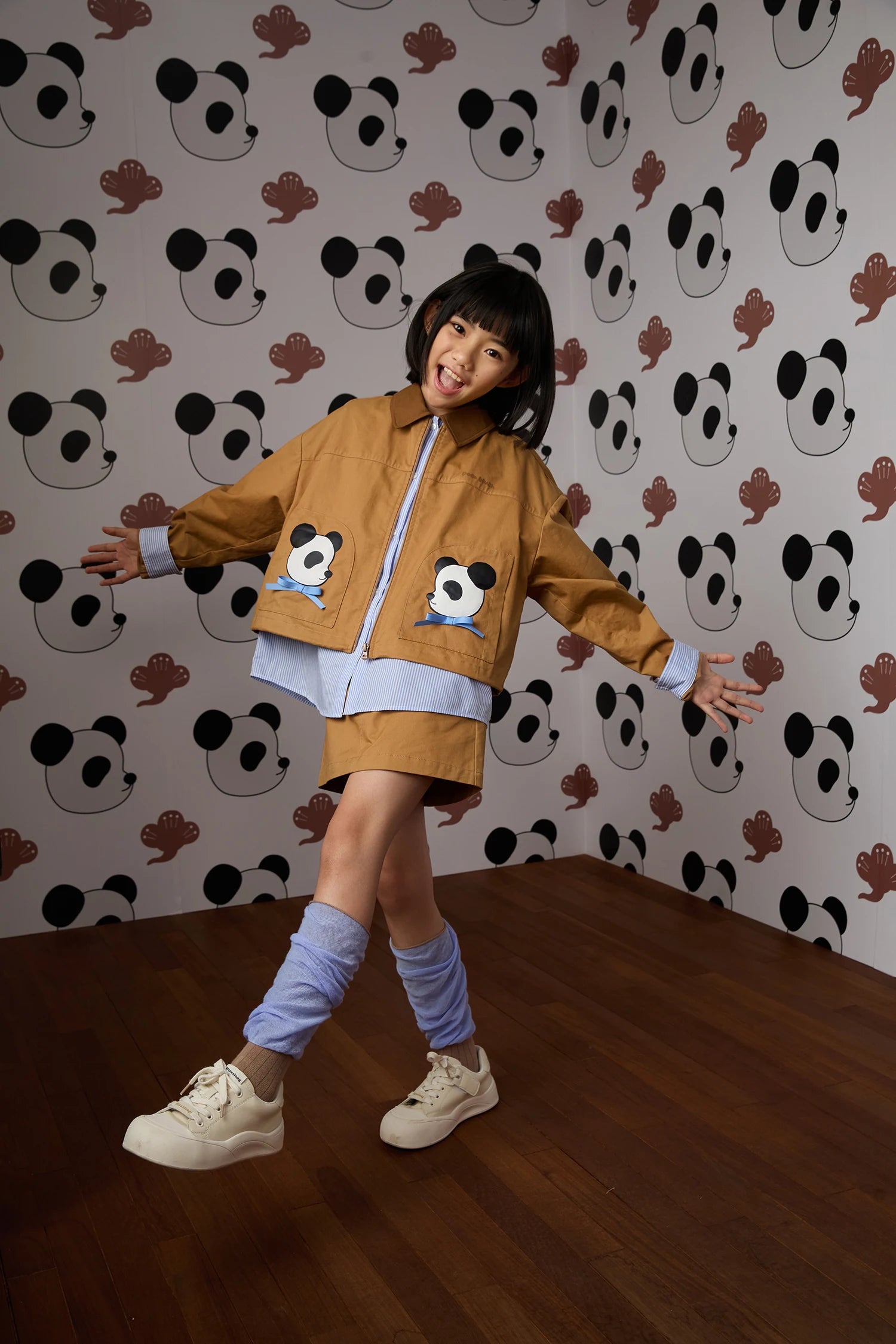 Panda layered jacket with caramel skort and blue colour-block socks; full styled look